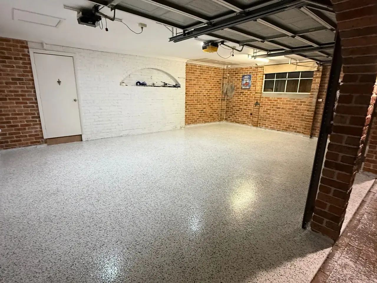 Decorative flake epoxy floor in a brick-walled garage at night — King of Seal Sydney
